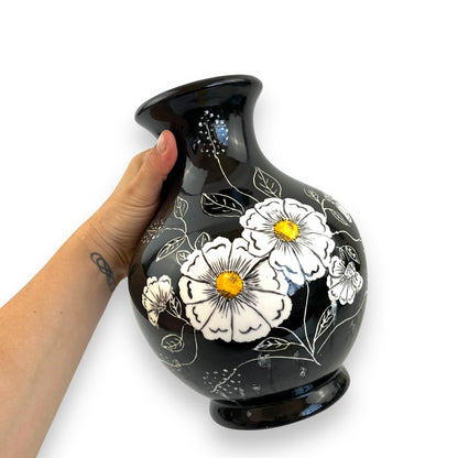 Large black vase with white and yellow flower artwork