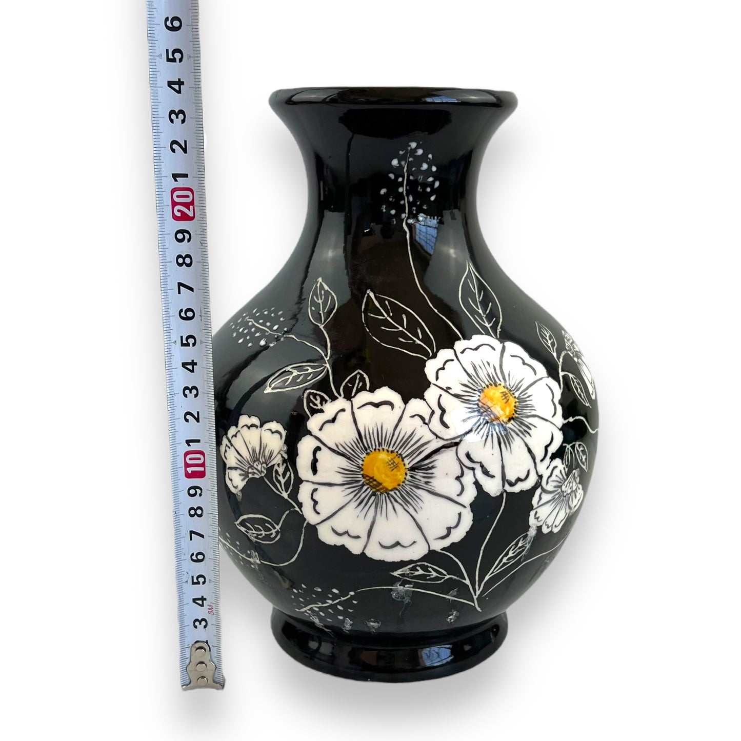 Large black vase with white and yellow flower artwork